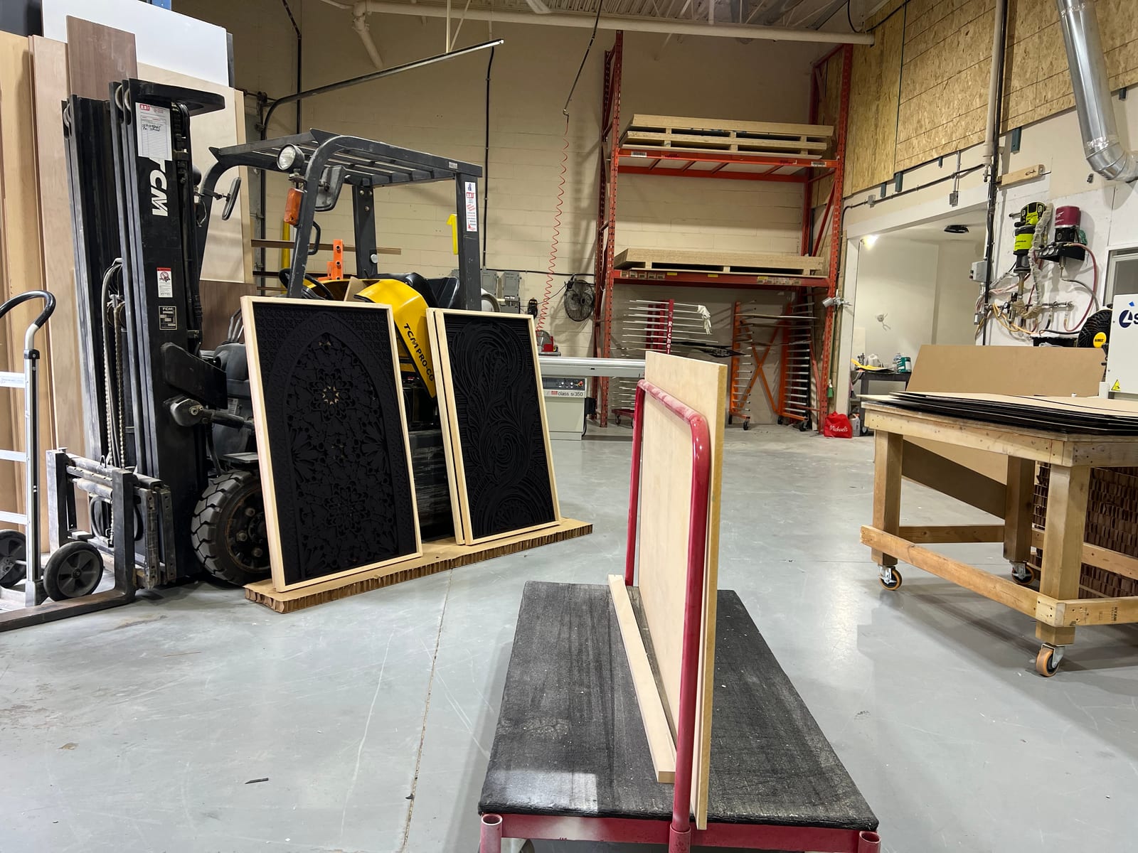 Wide shot of the workshop with framed pieces stacked against the wall.