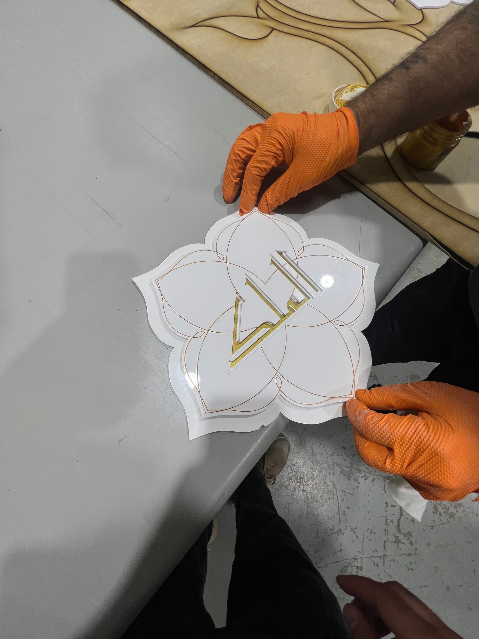 Orange-gloved hands placing the white-and-gold front layer.